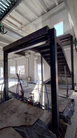 Ponteggi da cantiere all'interno di un edificio in fase di ristrutturazione, con travi a vista e pareti non rifinite.