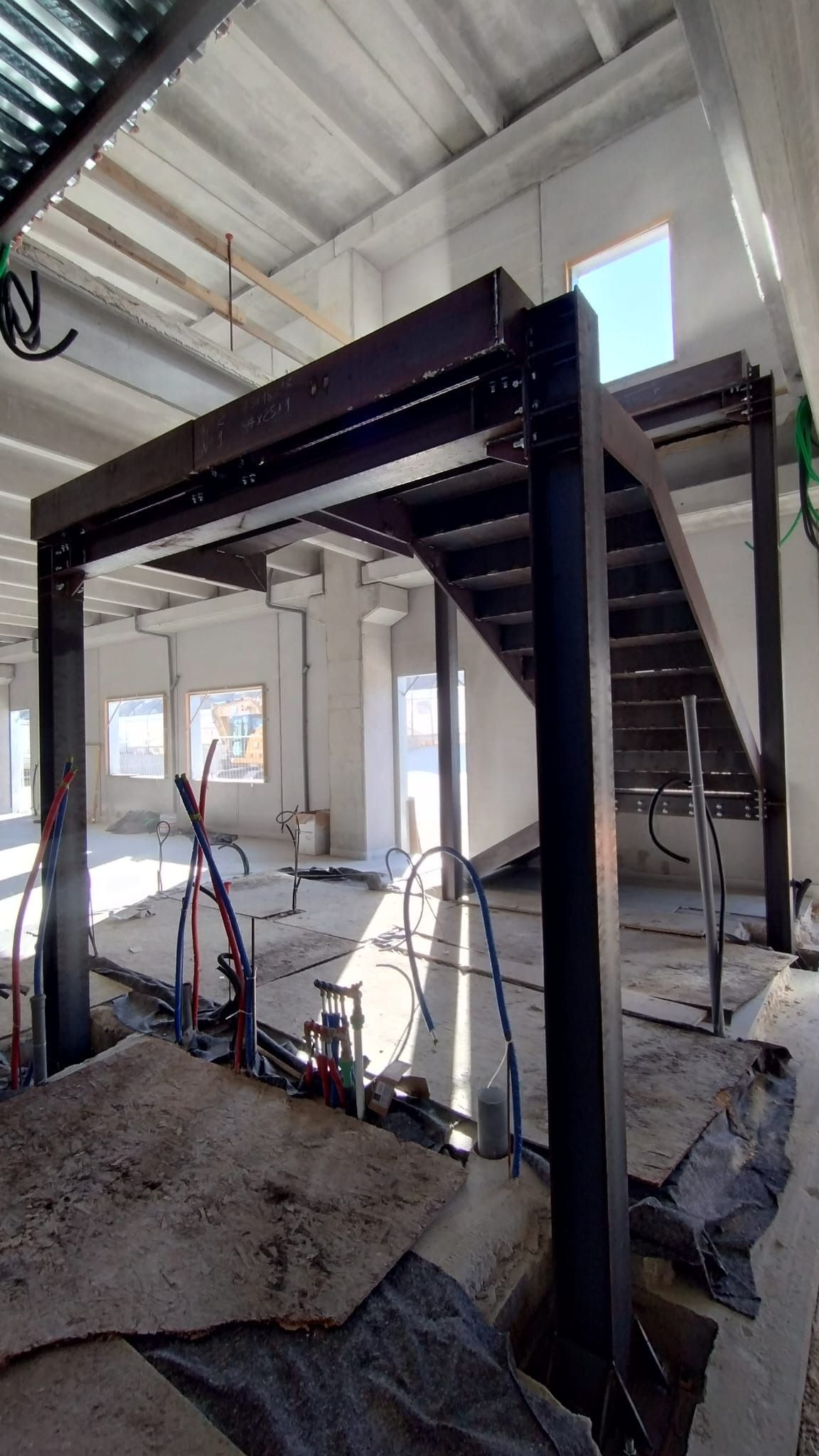Cantiere edile interno con scale a telaio in acciaio e pareti a vista in un edificio non finito