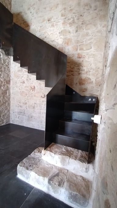 Scala in pietra con gradini in legno scuro in un angolo rustico degli interni.