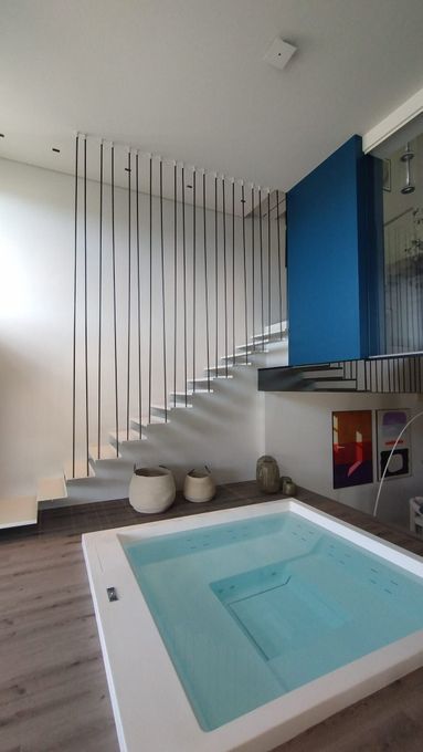 Sala biliardo interna moderna con scale bianche, parete decorativa blu e piccola piscina quadrata.