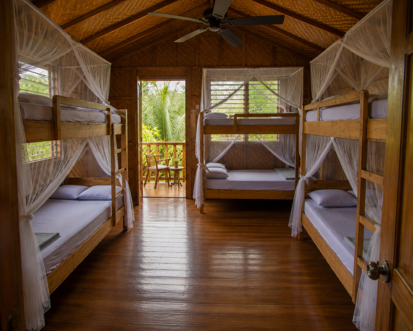 Cozy wooden bunk room with mosquito nets and an open door to a tropical balcony