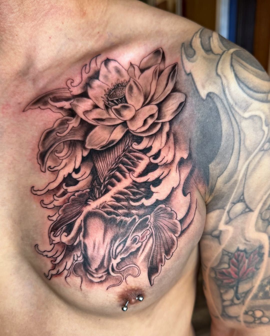 Black-and-gray floral tattoo on a chest, with a detailed flower and swirling ornamental design