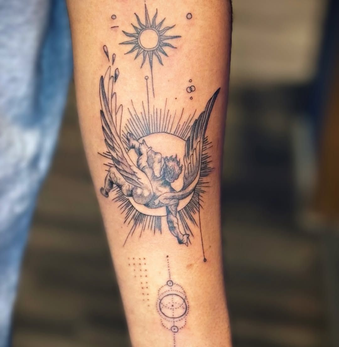 A fine-line tattoo on an arm featuring a winged figure, a sun symbol, and geometric shapes in black ink.