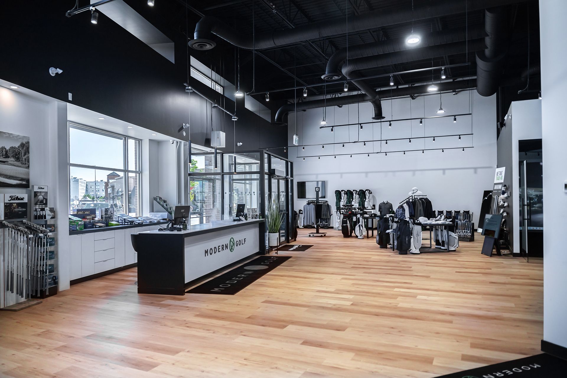 Interior of a modern retail store with wooden floors and black and white accents, featuring merchandise and a reception desk.
