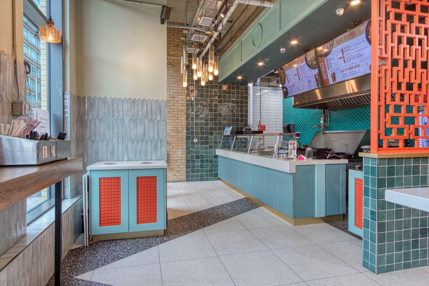 Interior of a cafe with turquoise and orange accents. Includes a counter, tiled walls, and a decorative cabinet.
