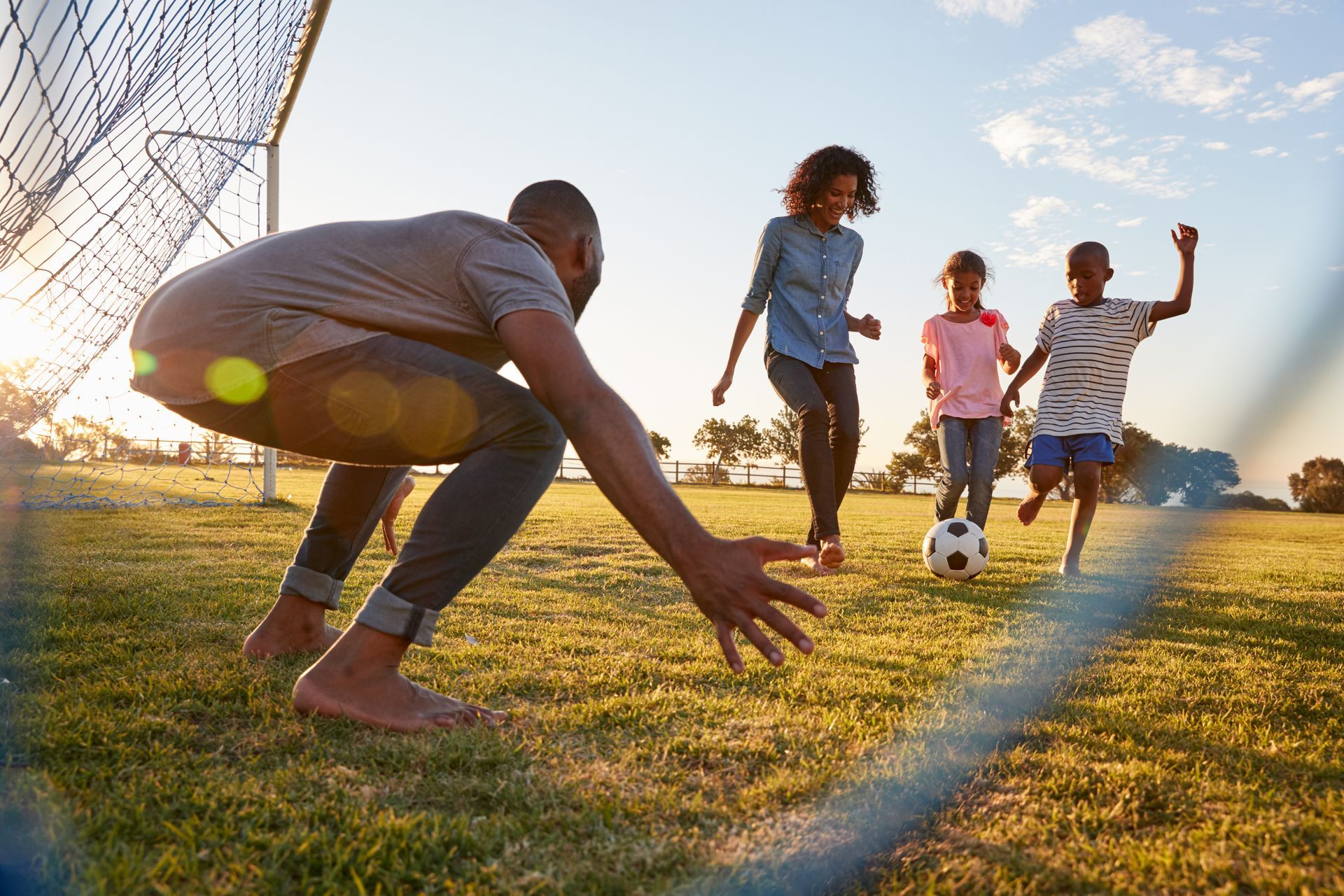 A dad playing soccer with 3 of his kids.