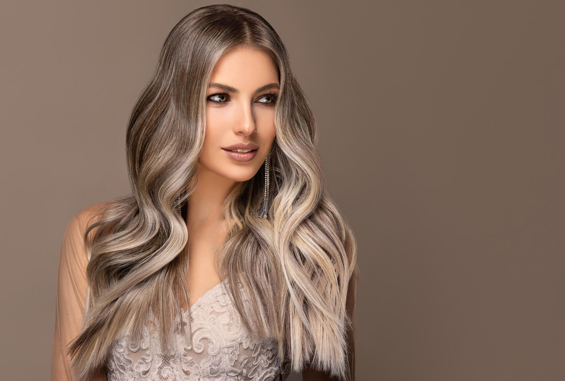 Portrait of a woman with long wavy blonde hair against a plain brown background