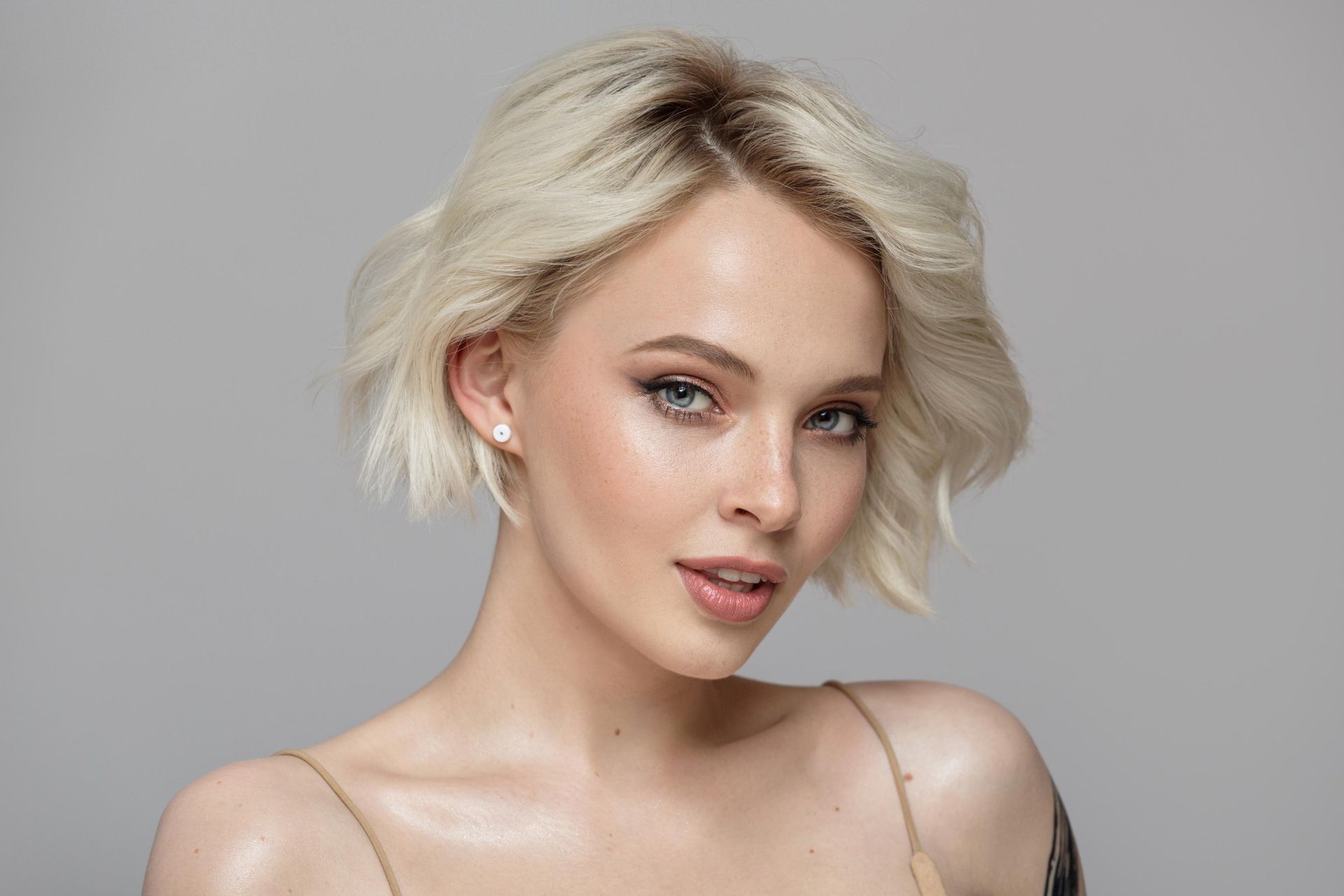 Portrait of a blonde woman with short wavy hair against a gray background