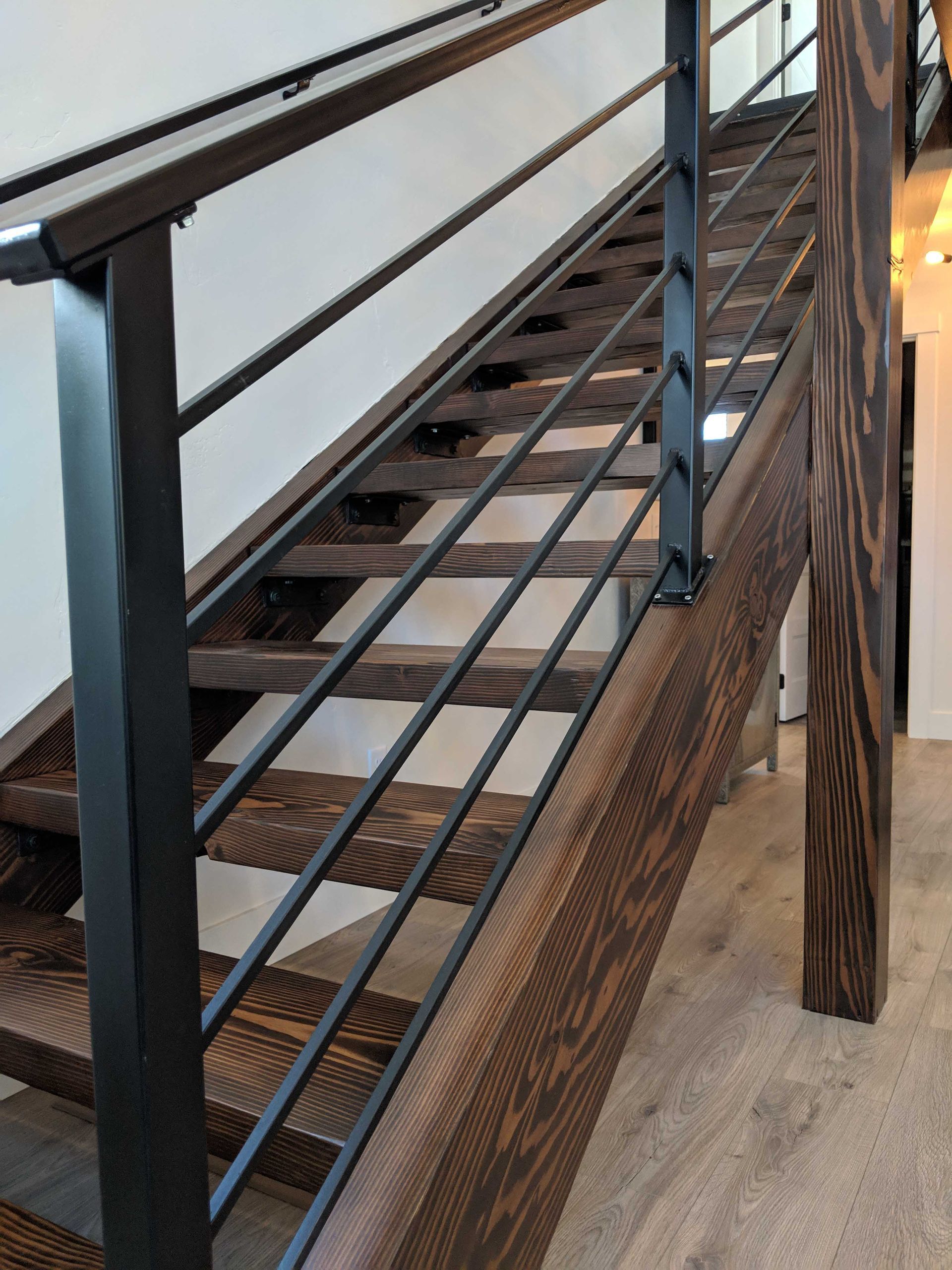 Modern staircase with dark wood treads and a black metal railing with horizontal bars.