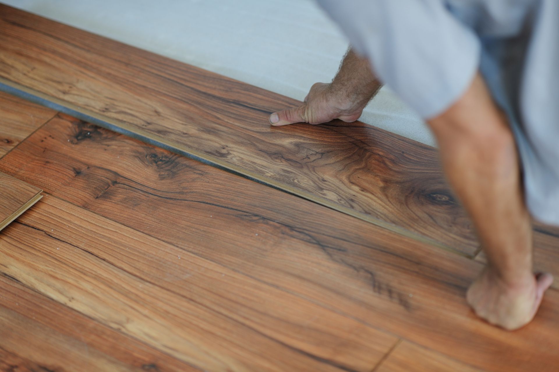 A man is installing a wooden floor in a room.