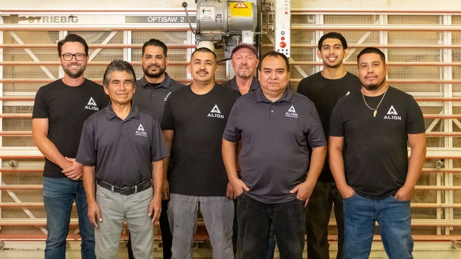Smiling person in brown ALIGN shirt giving thumbs up in a cabinet workshop