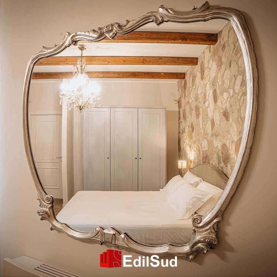 Bagno moderno con lavabo bianco, grande specchio, applique e una piccola finestra.