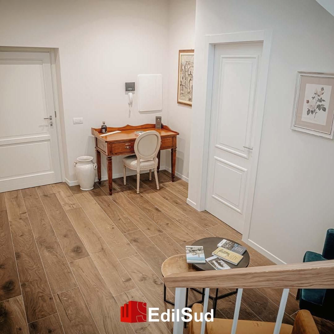 Moderna sala spa con lettino da massaggio, applique a parete, pavimento in legno e nicchie ad arco con asciugamani.