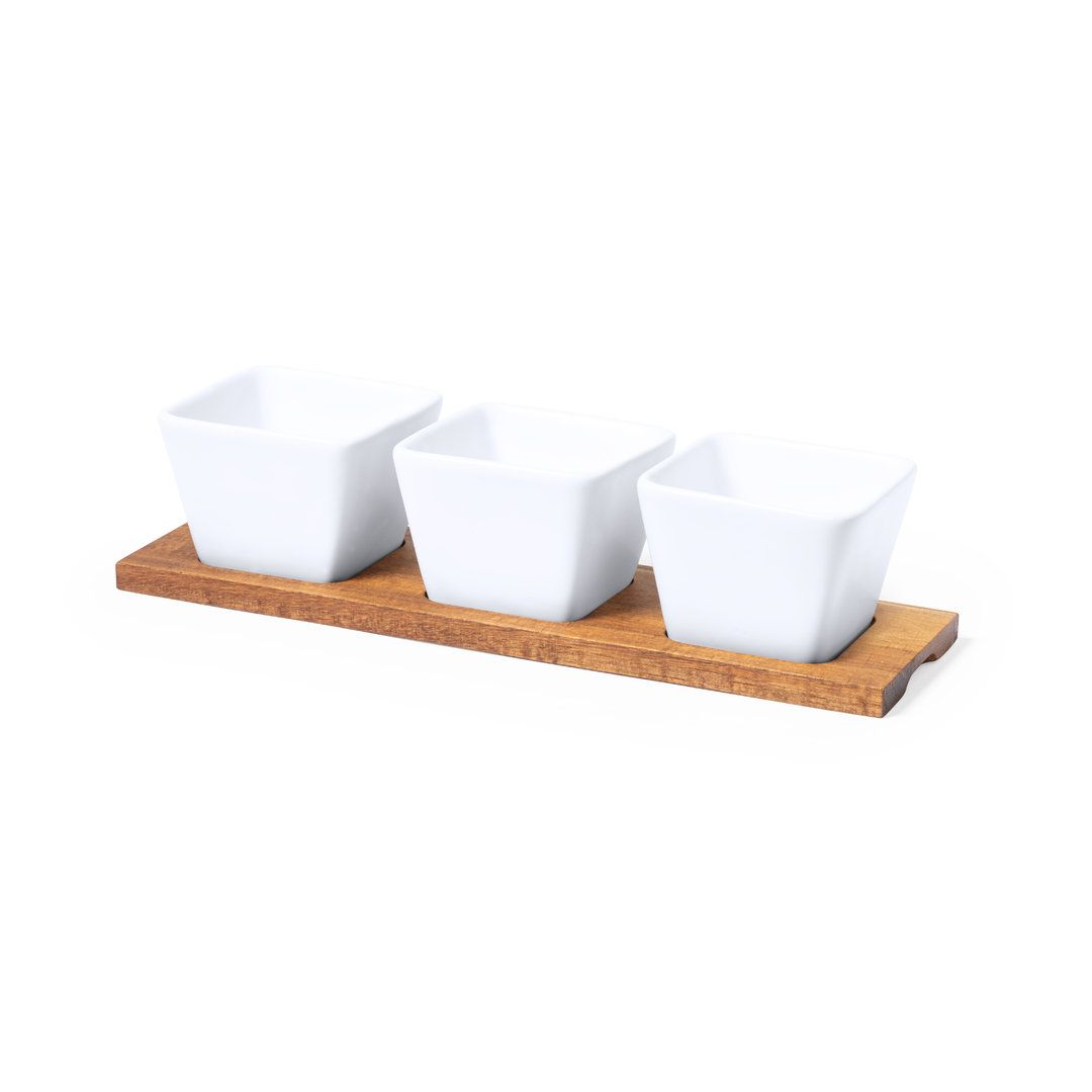 Tres pequeños cuencos cuadrados de cerámica blanca sobre una bandeja rectangular de madera marrón texturizada.