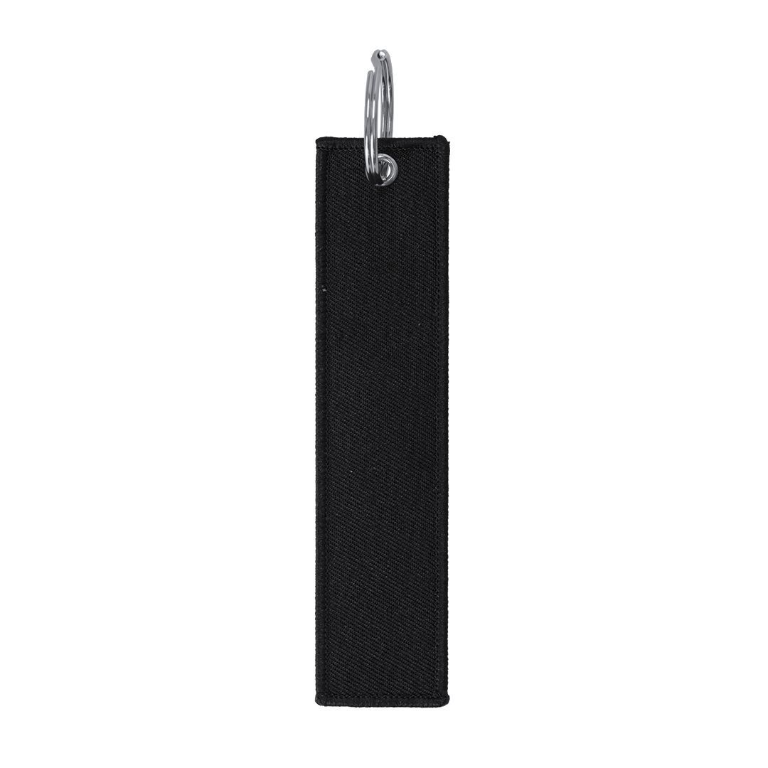 Un llavero rectangular liso de tela negra con una anilla metálica plateada en la parte superior sobre un fondo blanco.