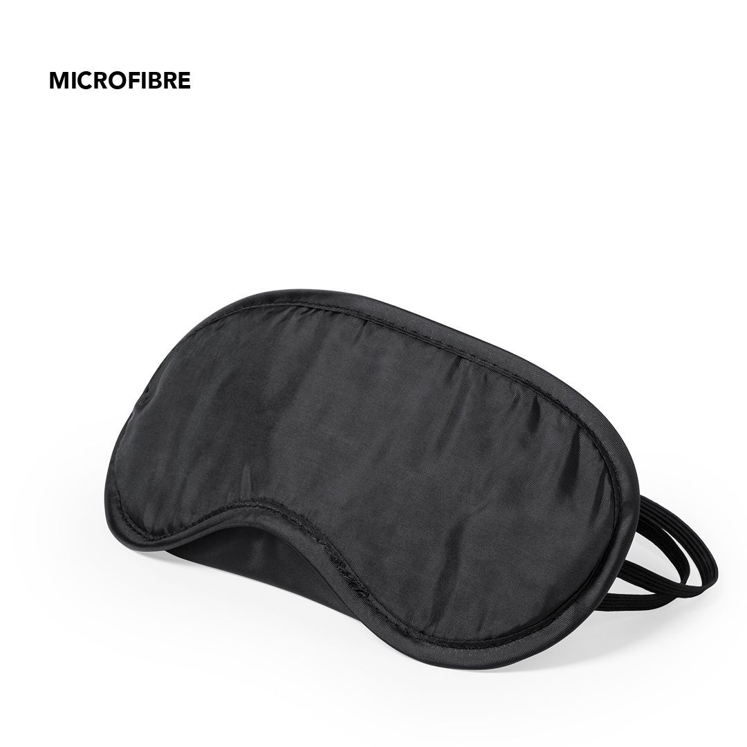 Antifaz para dormir de microfibra negra, visto desde un ángulo sobre un fondo blanco.