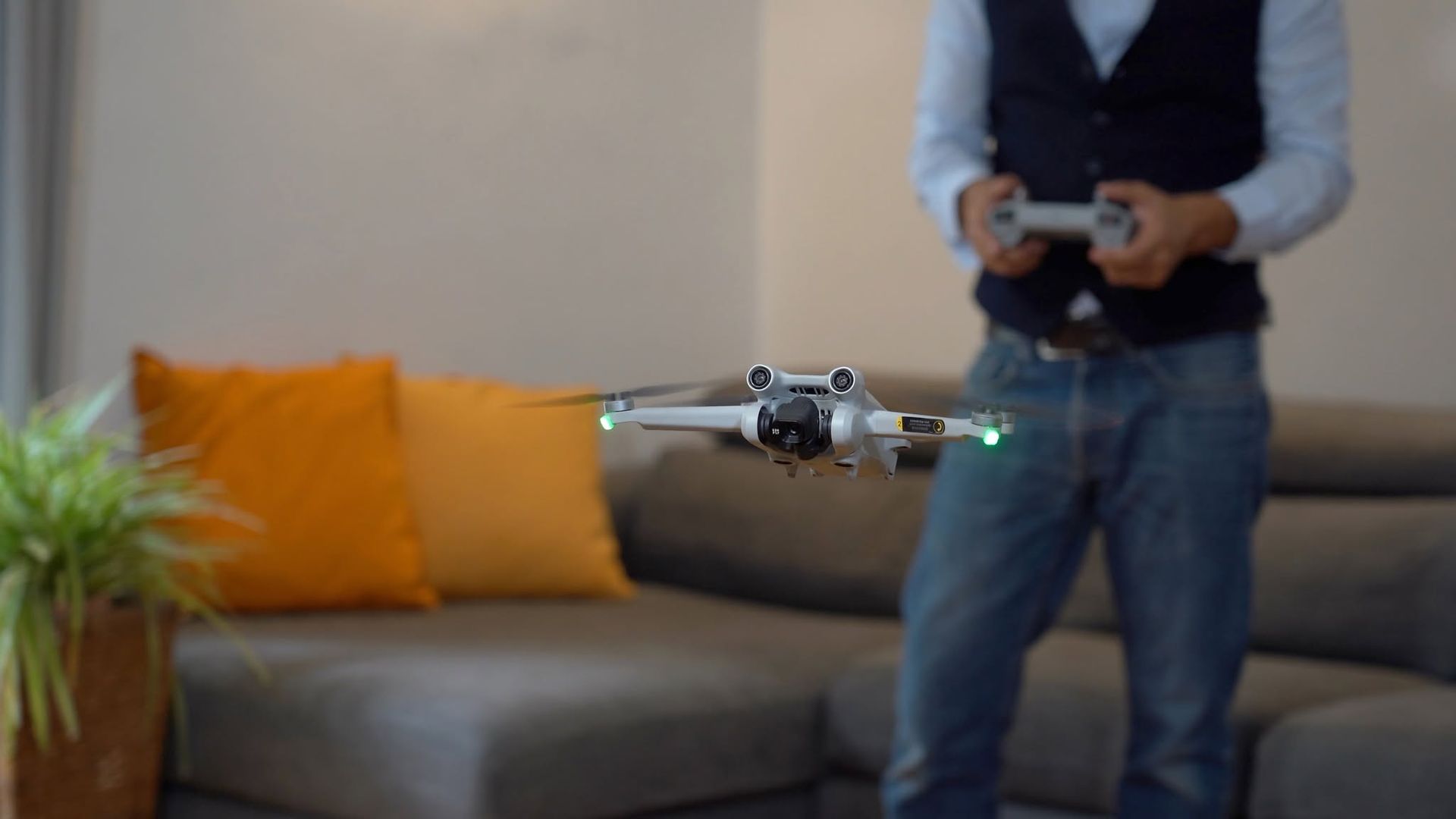 Drone hovering in a living room as a person controls it with a remote.