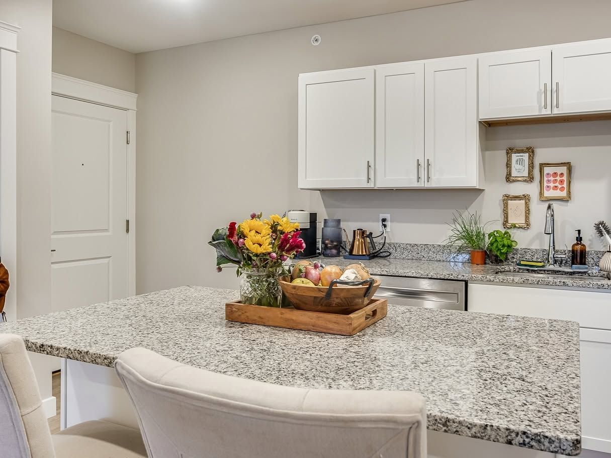 Modern kitchen with white cabinets, speckled island countertop, and a flower arrangement on the counter