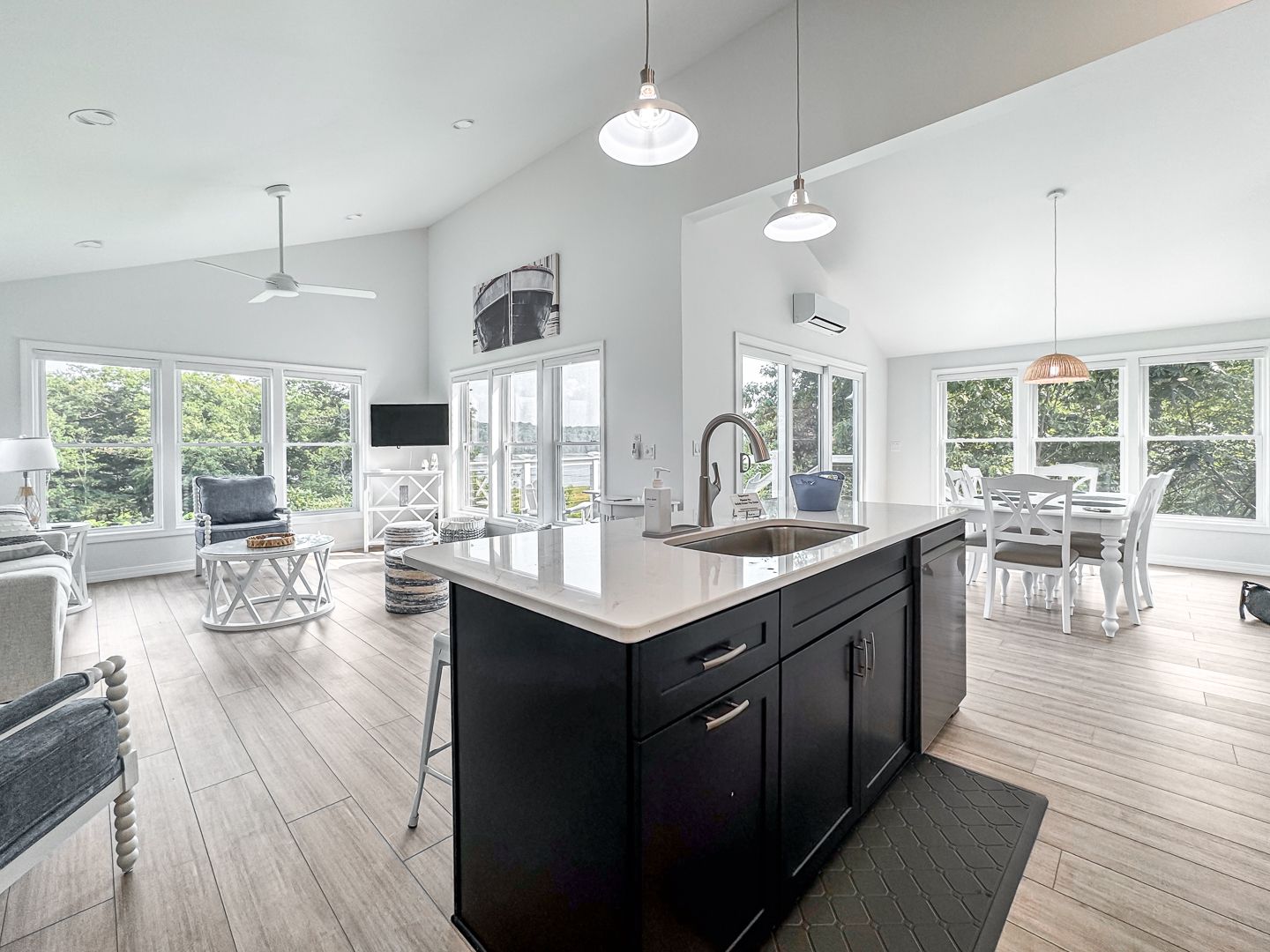 Bright open kitchen with black island, white cabinets, and adjacent dining and sitting areas