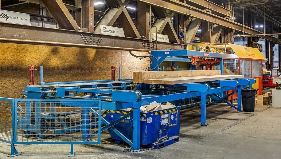 Blue industrial conveyor machinery in a factory, with metal frames and railings under overhead lights