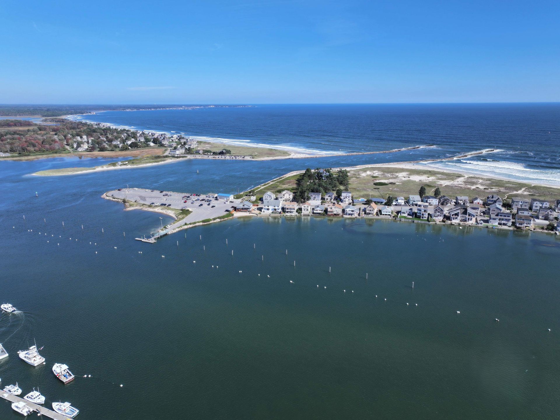 Aerial view of a coastal inlet with blue water, sandy shore, and homes along the shoreline