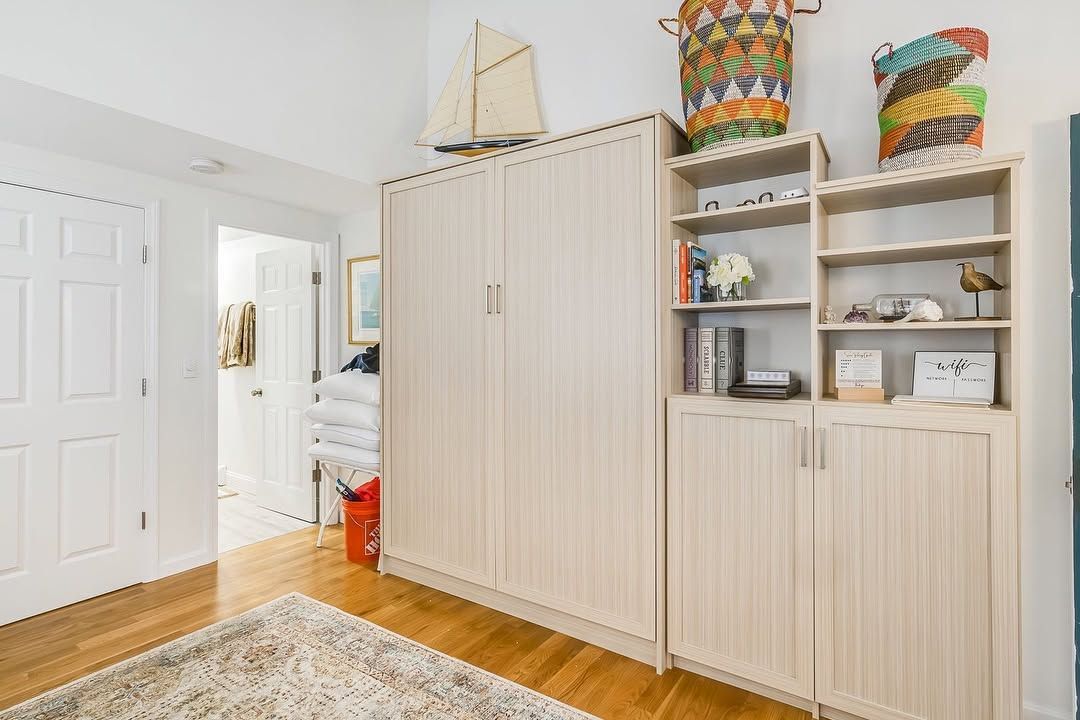 Bright hallway with white cabinets, shelves, woven baskets, and a sailboat decoration on top