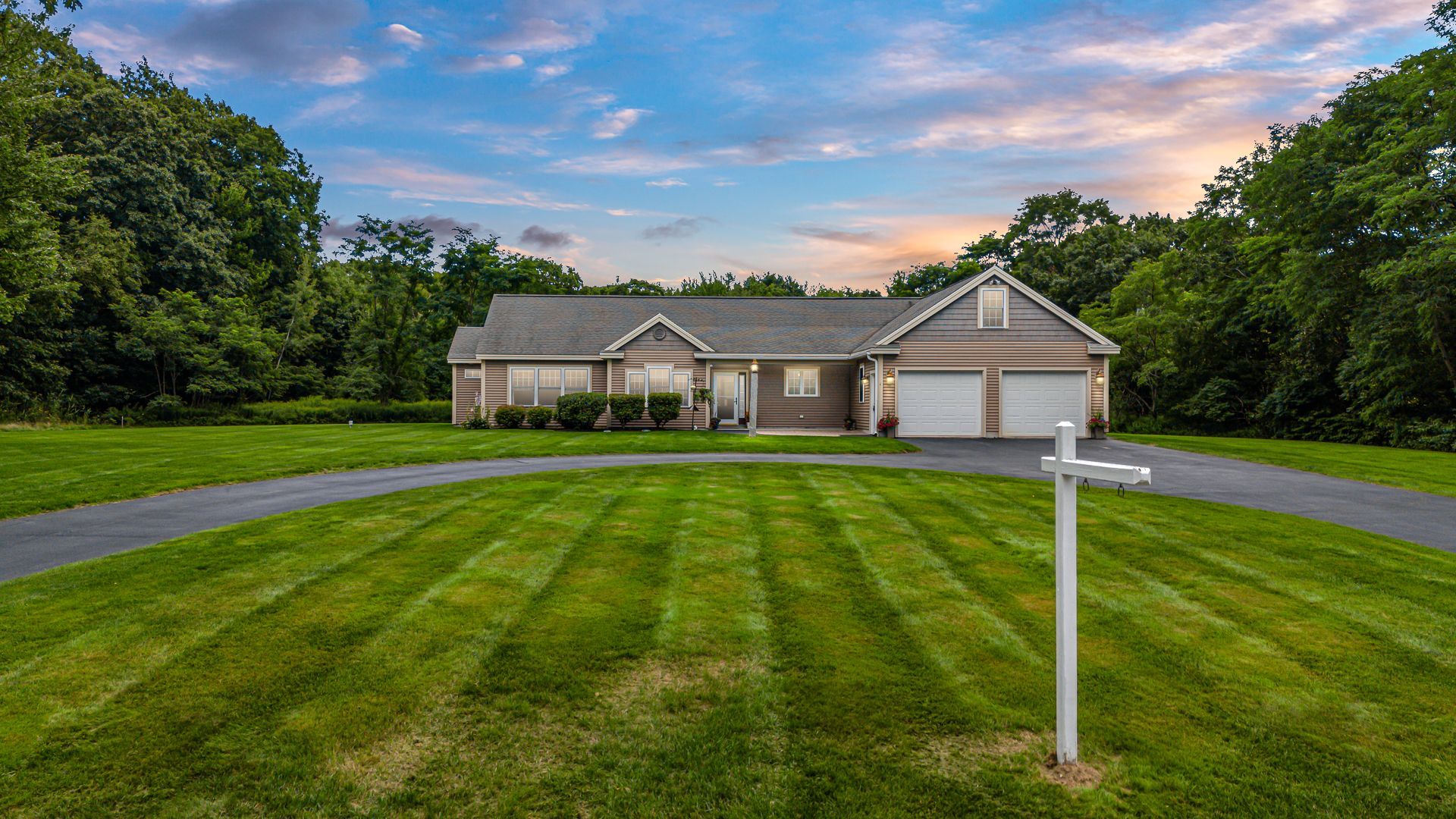 Suburban house with a two-car garage and striped green lawn at sunset