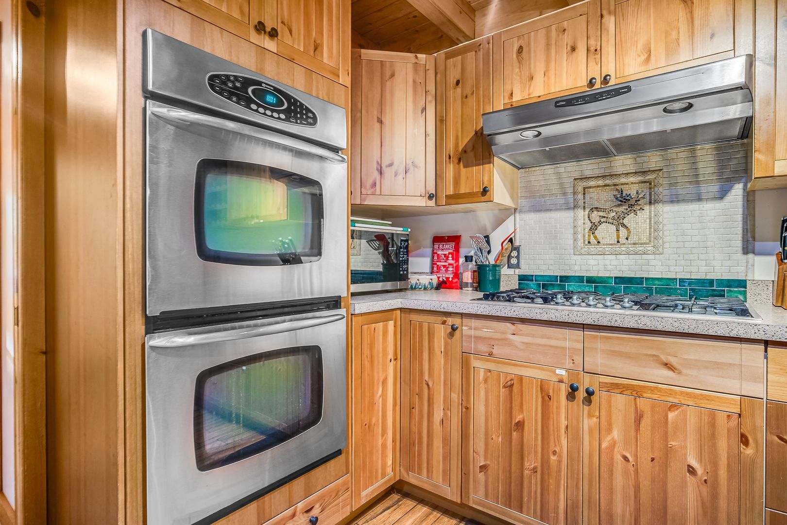 Wood-paneled kitchen with double wall oven, countertop, and tiled backsplash