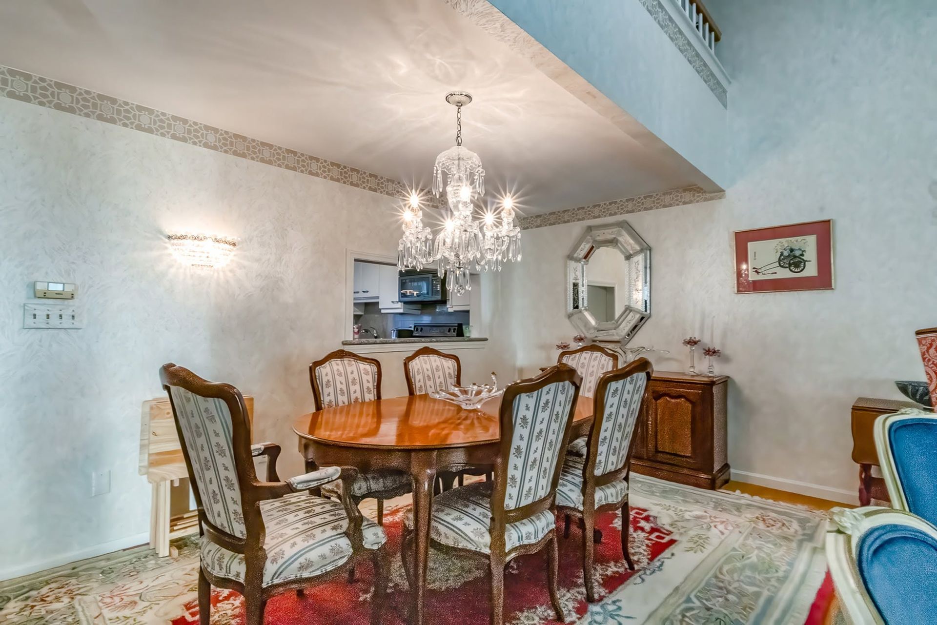 Elegant dining room with wooden table, patterned chairs, chandelier, and wall mirror