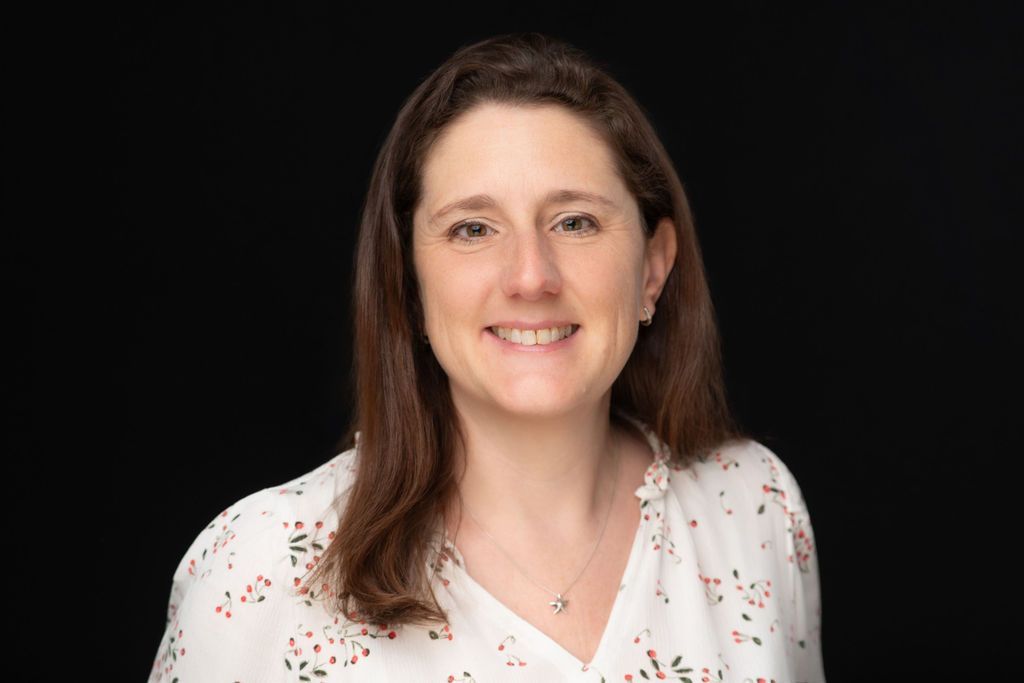 Portrait of a smiling woman in a white blouse with a black background