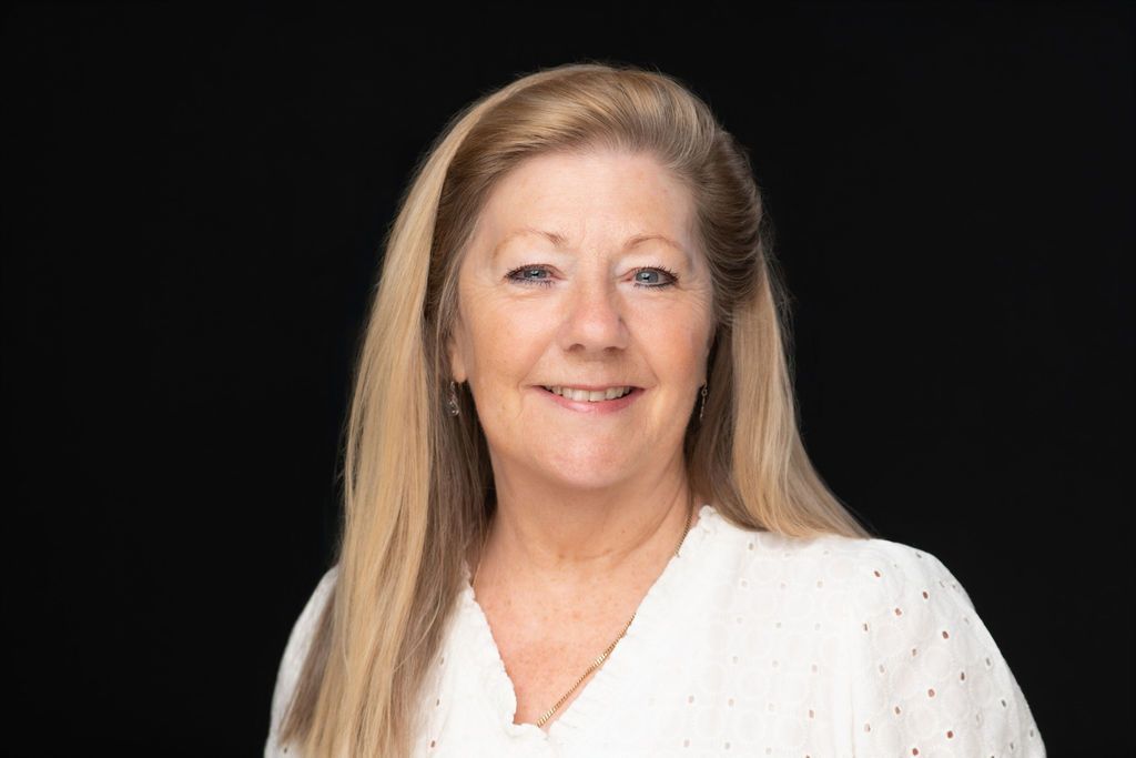 Smiling woman in a white blouse against a black background