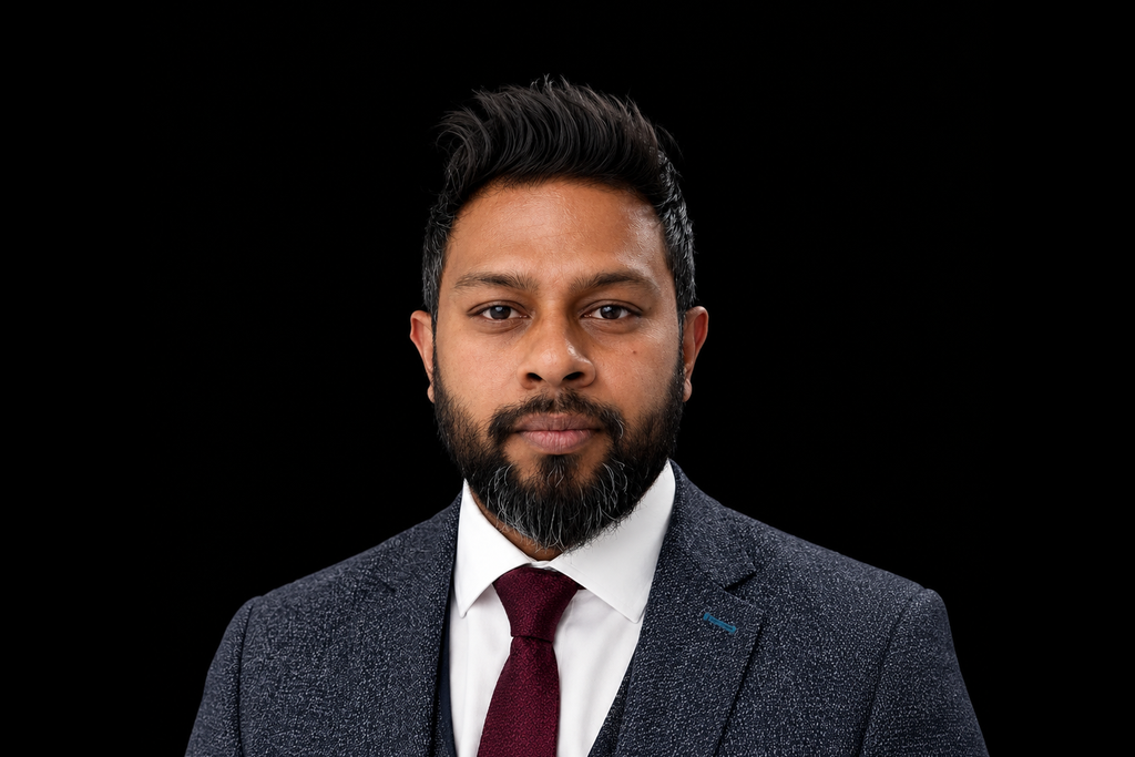 Formal portrait of a man in a dark suit, white shirt, and maroon tie against a black background