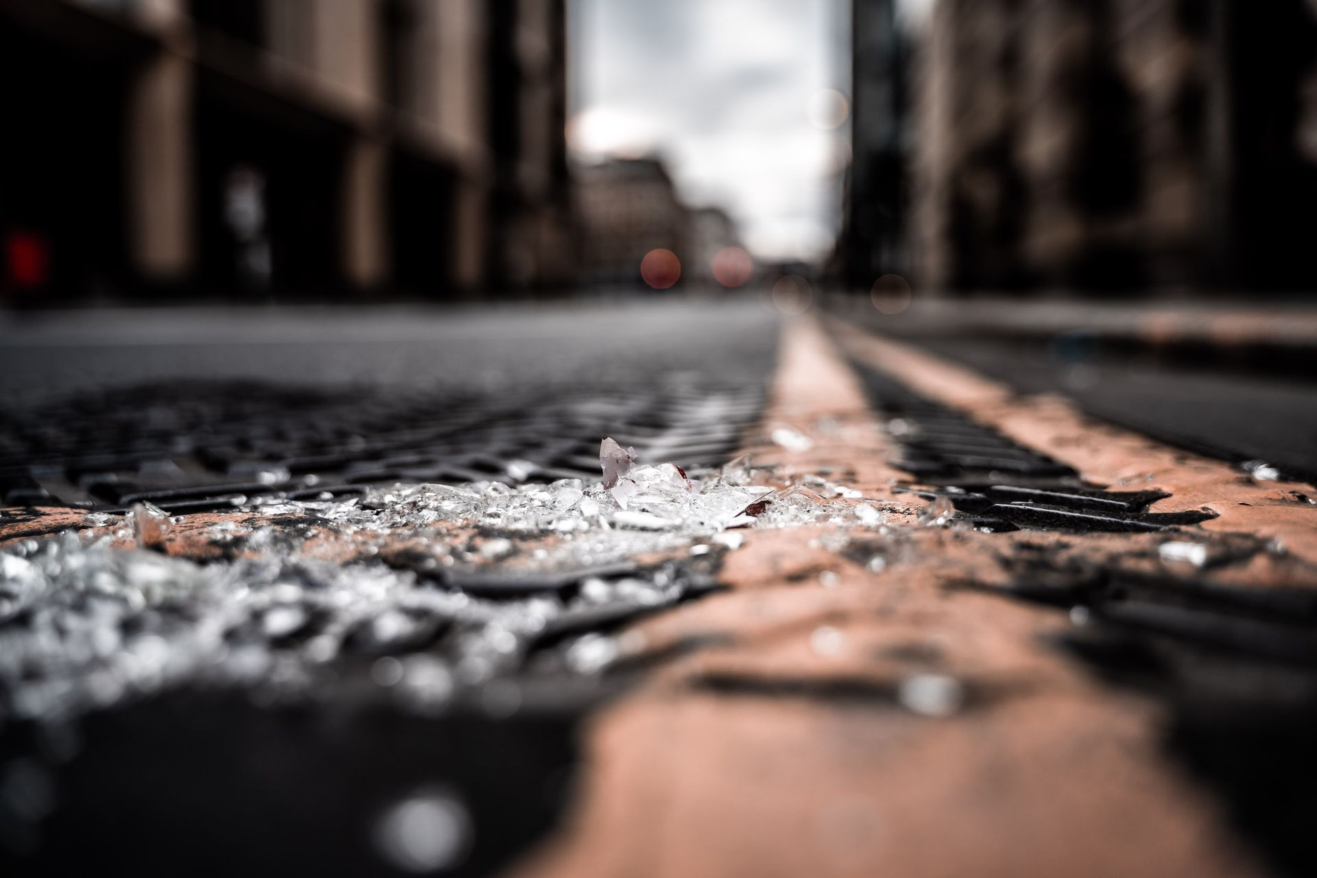 Low-angle view of a wet, cracked street with a blurred city background and road markings