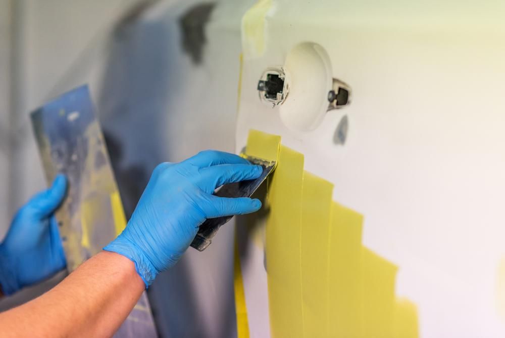 A Person Wearing Blue Gloves Is Sanding a Wall with A Sander — Southside Bodyworks in Greenway, ACT