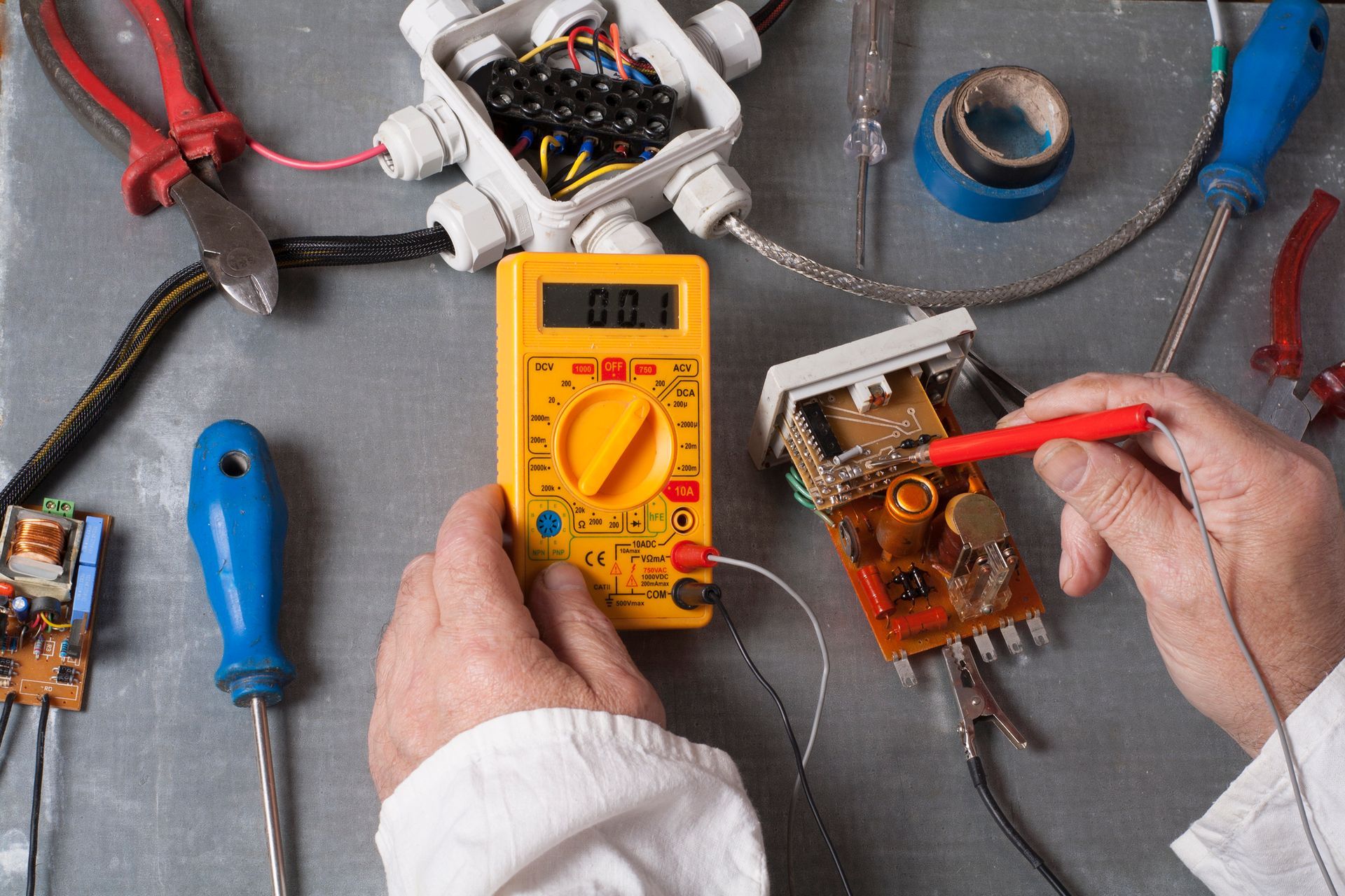 Electrician's hands using multimeter in electrical cabinet showcasing expert electrical services.