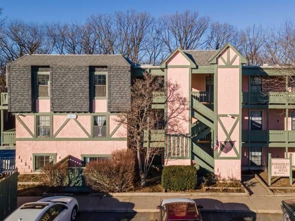 Apartment building exterior, pink and green trim, with parked cars in front.