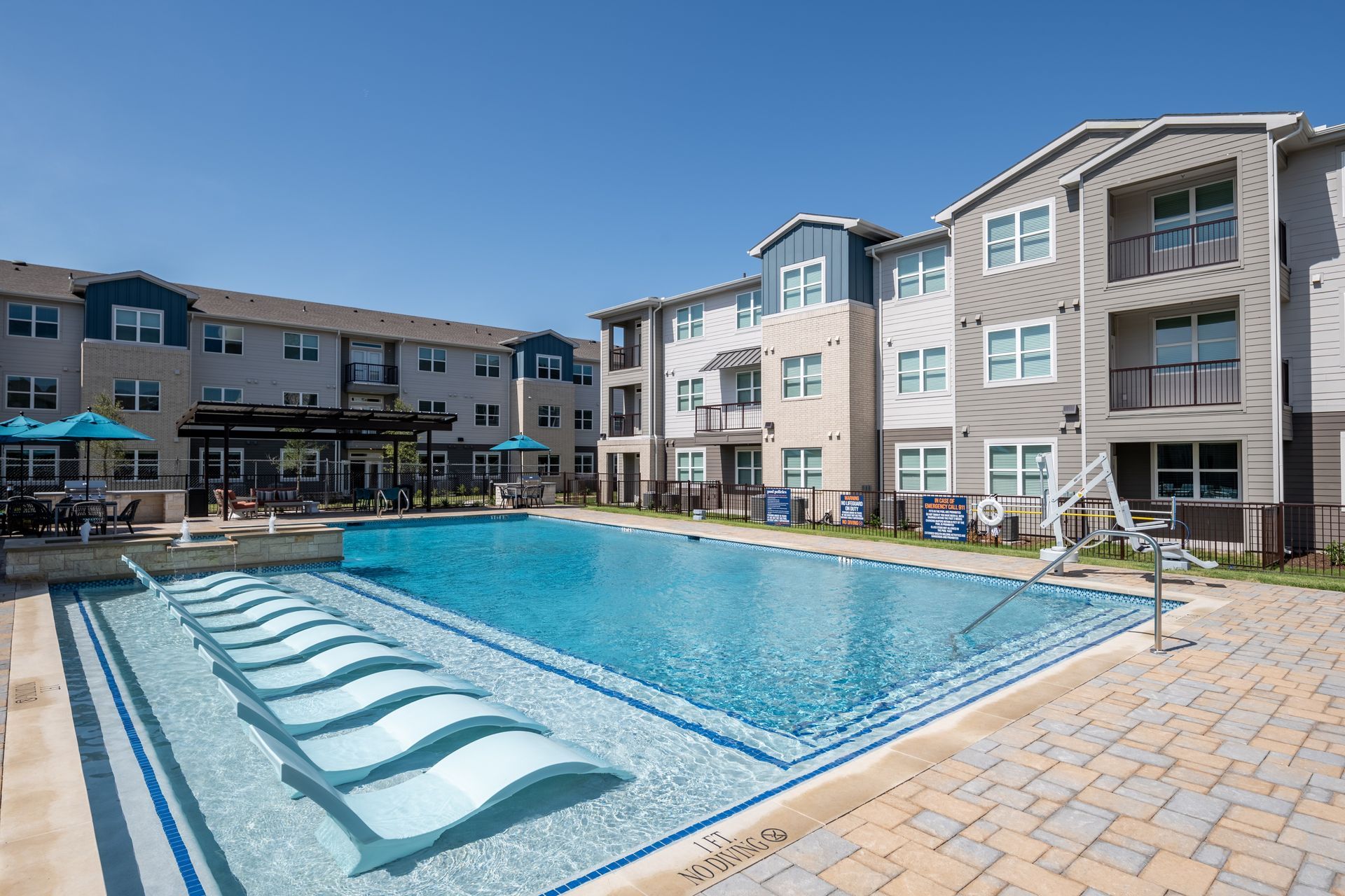 A large swimming pool in front of a large apartment building.