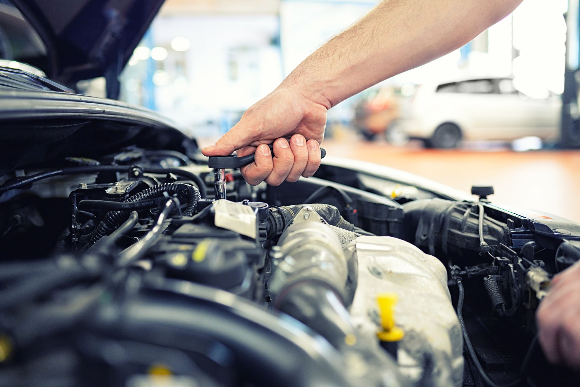 Mechanic using a wrench to work on a car engine in a garage
