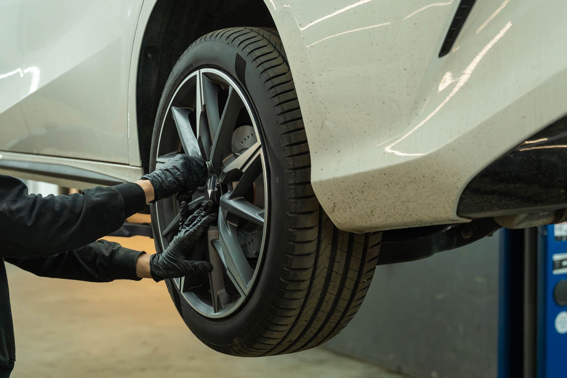 Mechanic removing a car wheel on a lift in a garage