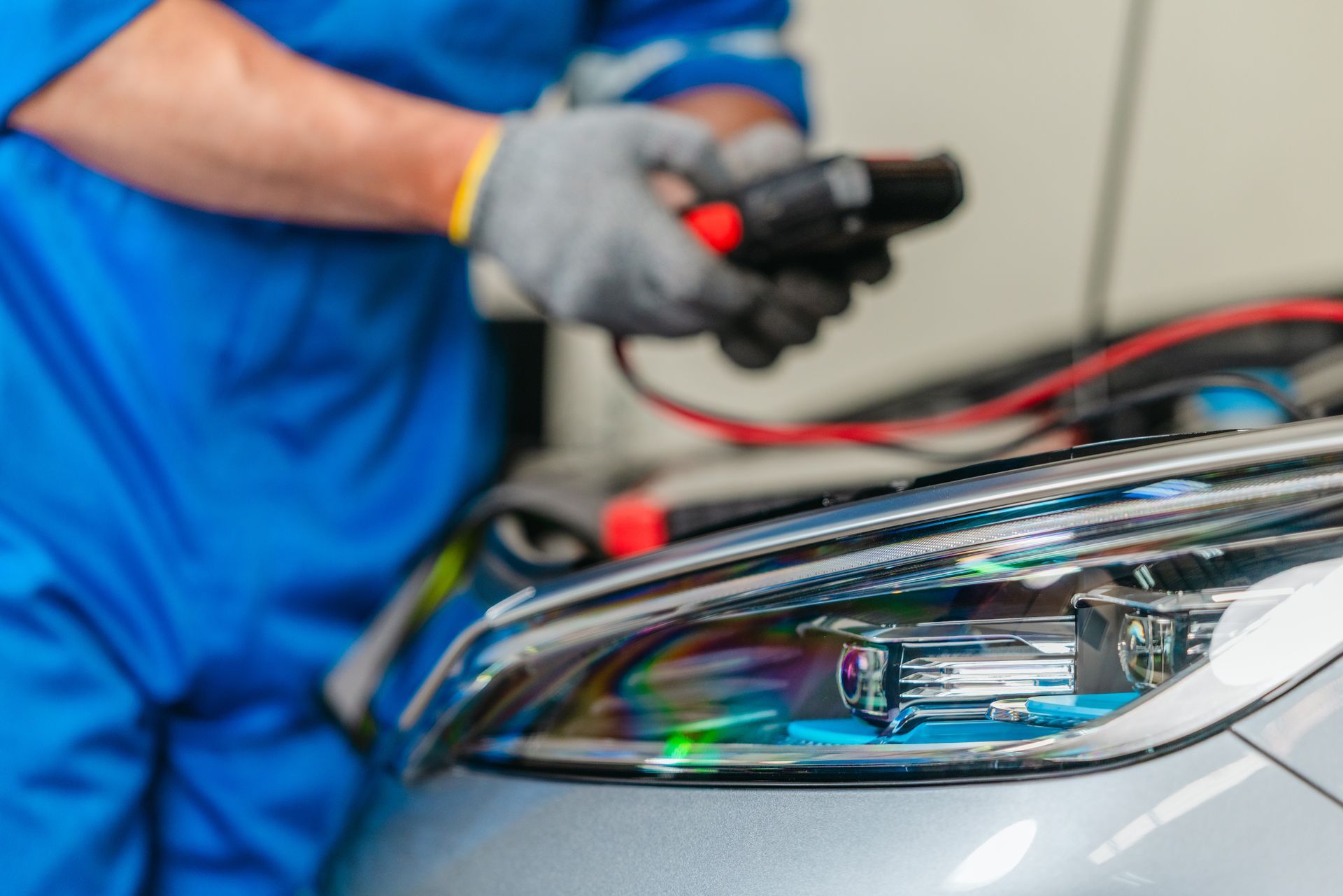 Mechanic using a laptop to diagnose a car engine in an auto repair shop