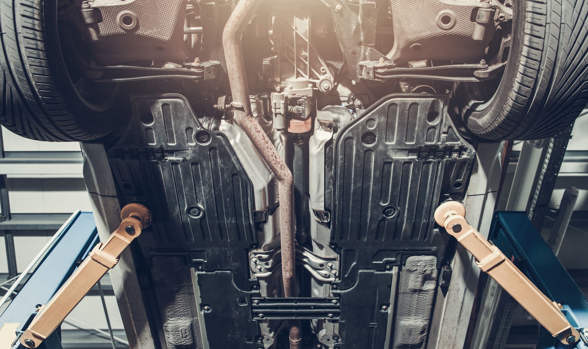 Undercar view of a car on a lift in a mechanic’s workshop, showing the chassis and suspension components.