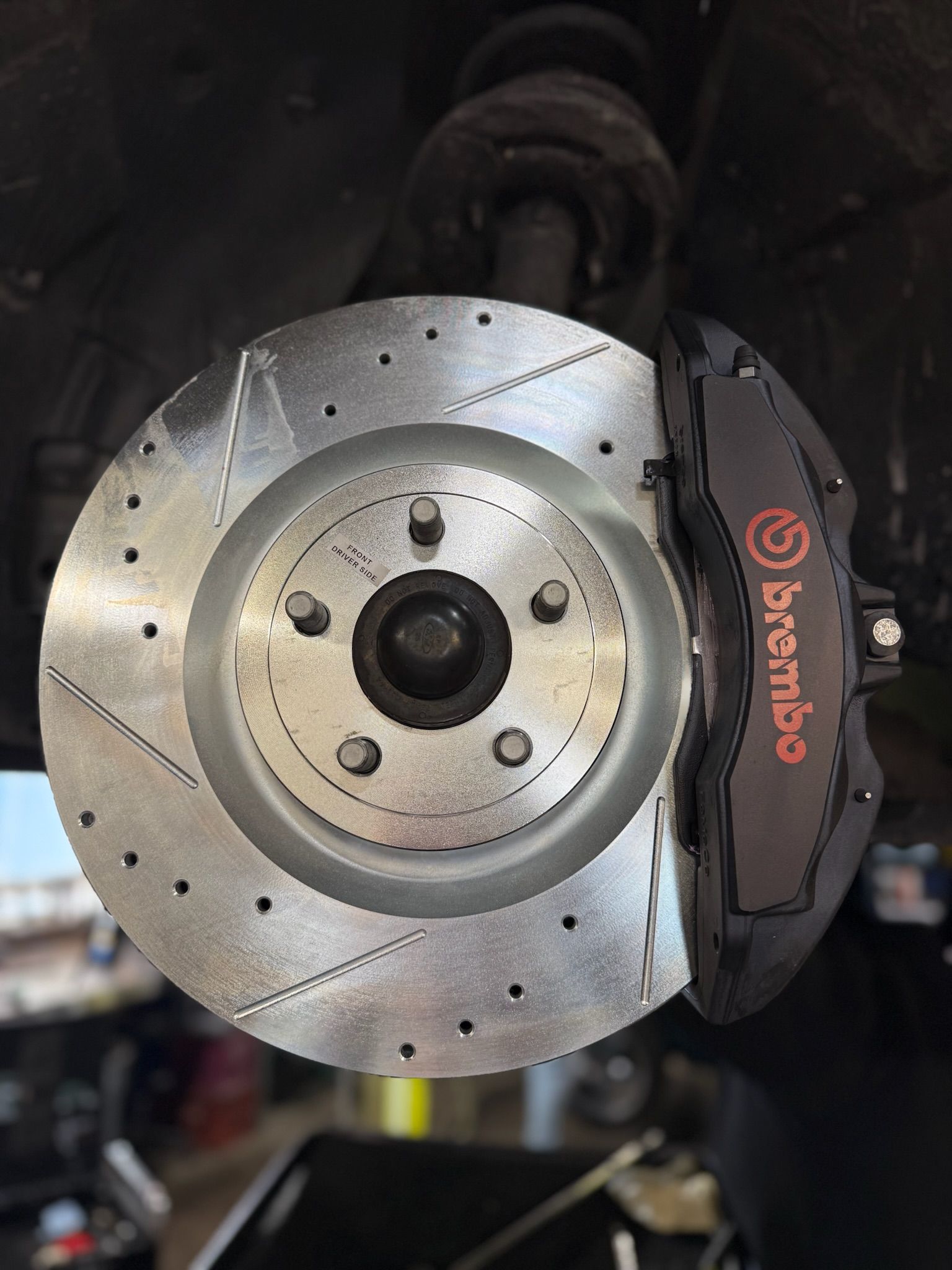 Close-up of a drilled brake rotor and Brembo caliper on a car wheel hub.