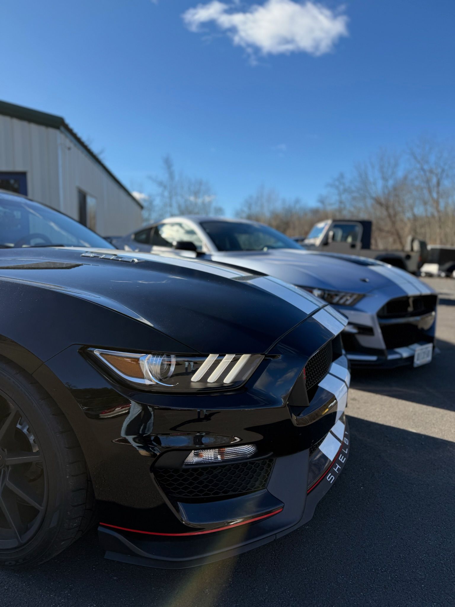Two black sports cars parked outdoors under a blue sky