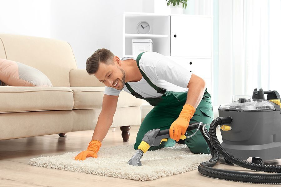a man is cleaning a rug with a vacuum