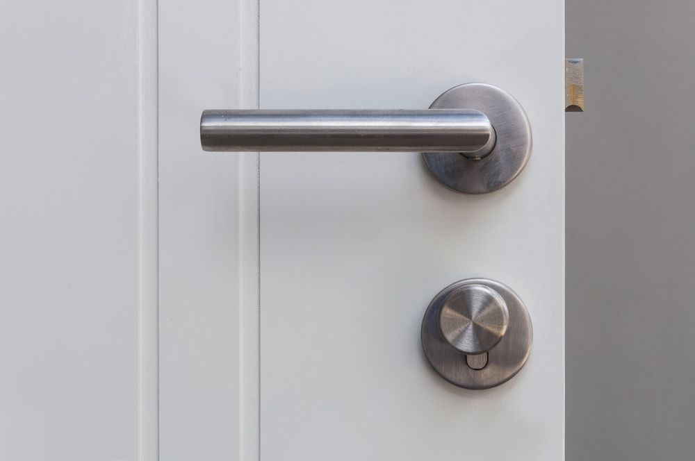 A Close Up of a Stainless Steel Door Handle on a White Door — Budget Screens & Awnings in Byron Bay, NSW