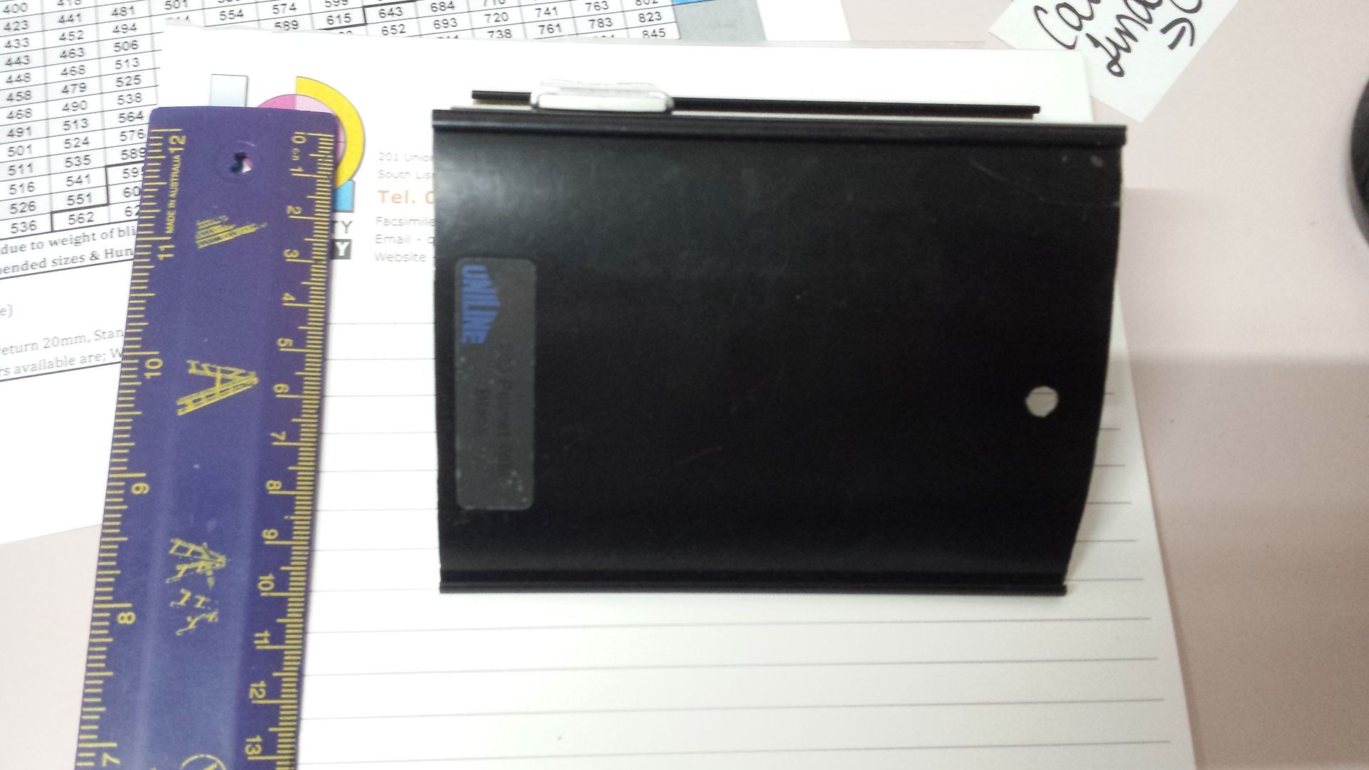 A black, rectangular device sits next to a purple ruler on lined paper — Budget Screens & Awnings in South Lismore, NSW
