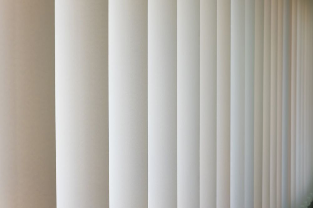 A Close Up of a Row of White Vertical Blinds on a Wall — Budget Screens & Awnings in Ballina, NSW