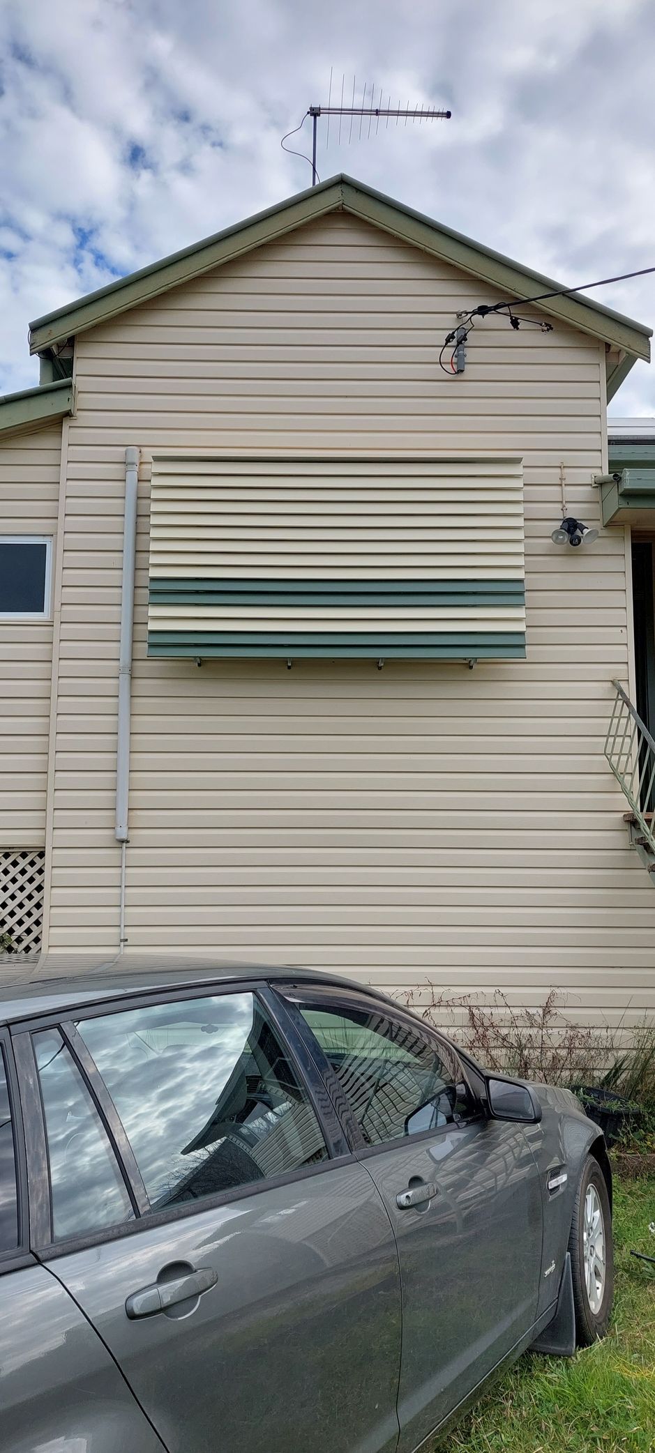 A striped exterior window awning mounted on a beige wall of a house — Budget Screens & Awnings in South Lismore, NSW