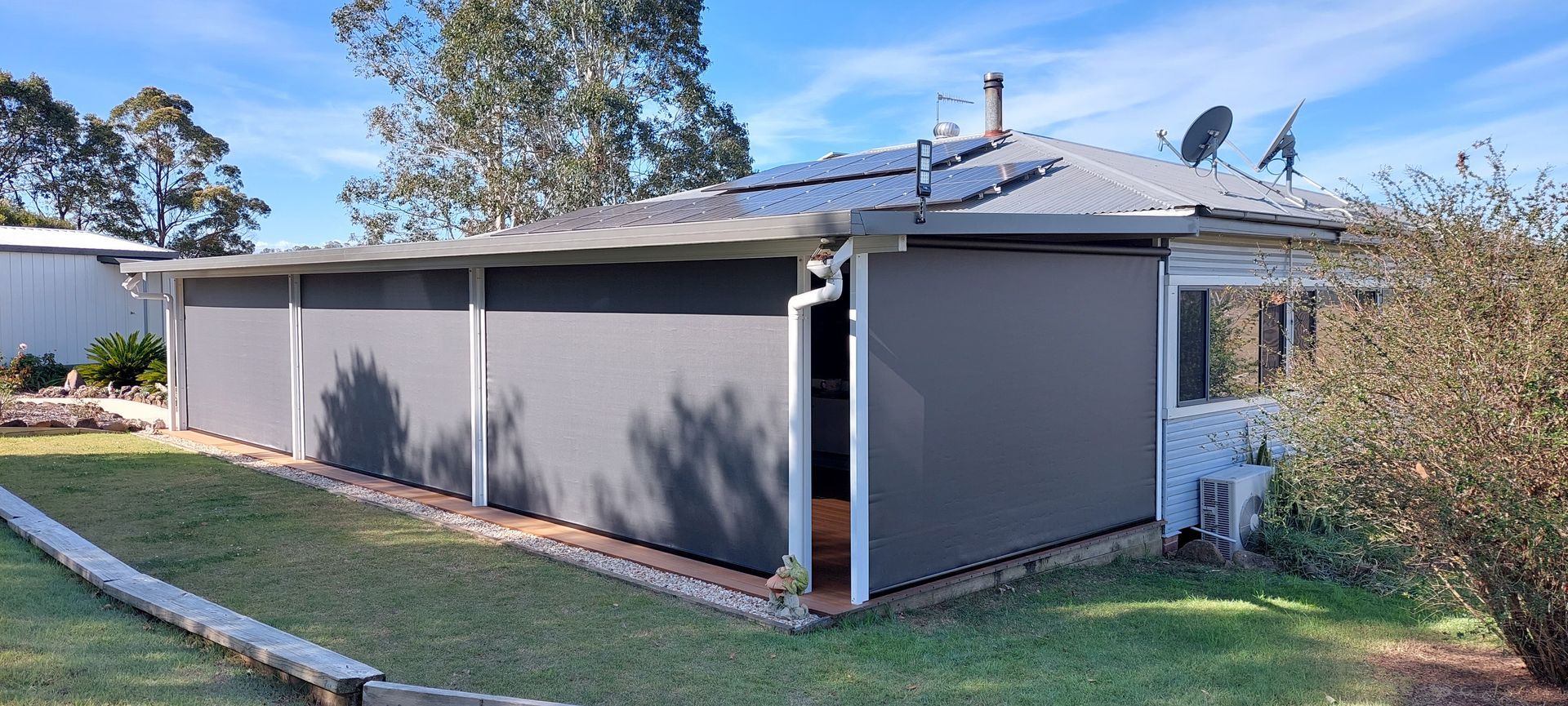 A house exterior enclosed by grey outdoor privacy blinds — Budget Screens & Awnings in South Lismore, NSW