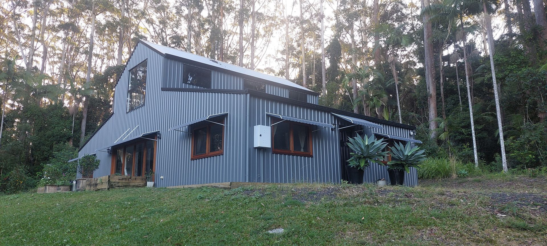 A grey, corrugated metal cabin with wood-trimmed windows — Budget Screens & Awnings in South Lismore, NSW